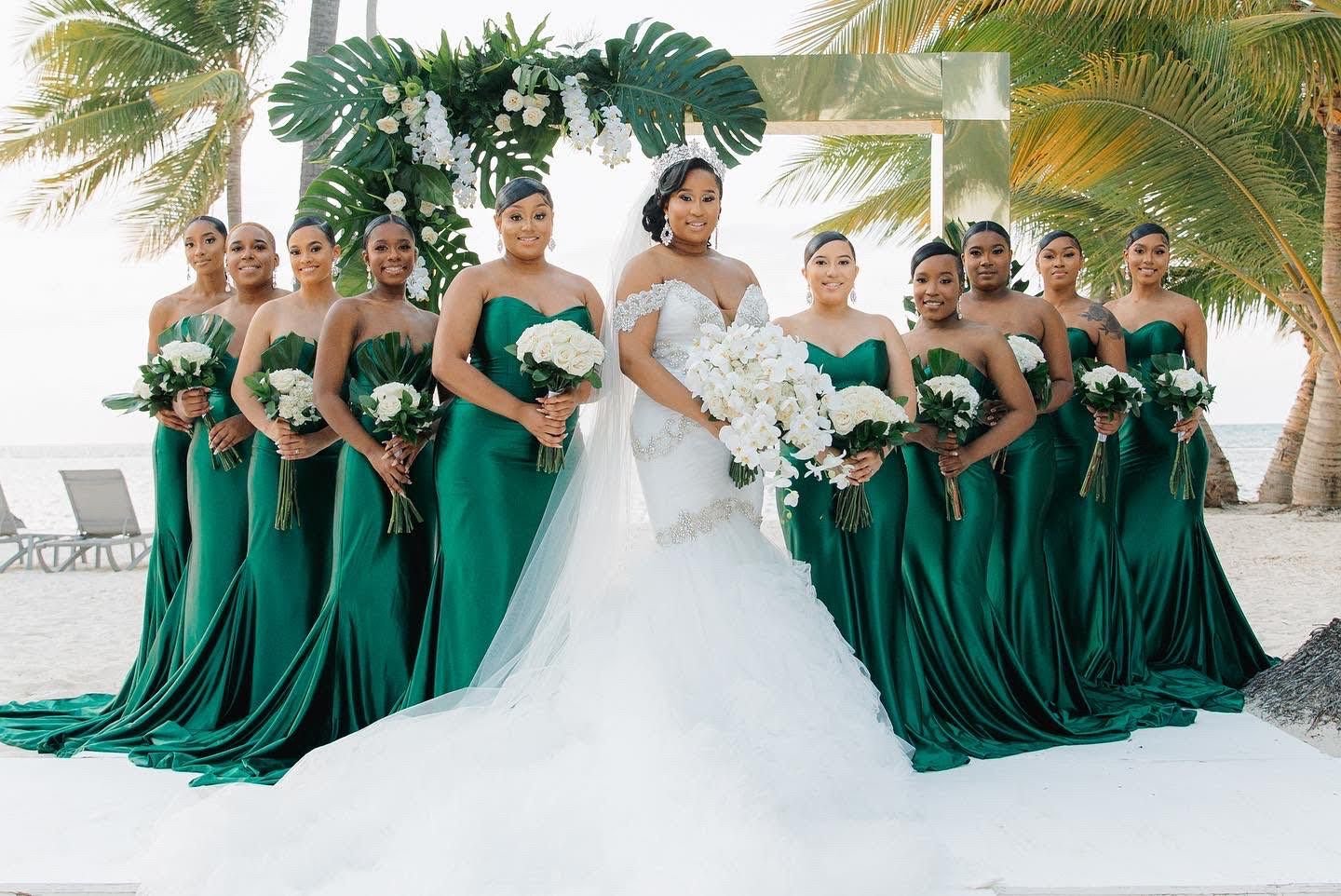 Bridesmaids in emerald green gowns at a beach wedding